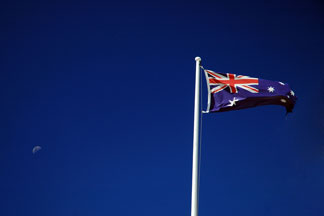 Australia flag flying with a deep blue sky background